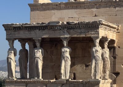 Row of Caryatid columns supporting the temple frieze against a clear blue sky, an ancient Greek monument.