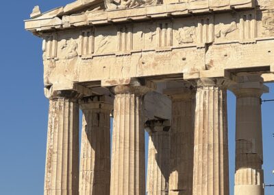 Ancient Greek temple with tall fluted Doric columns against a clear blue sky
