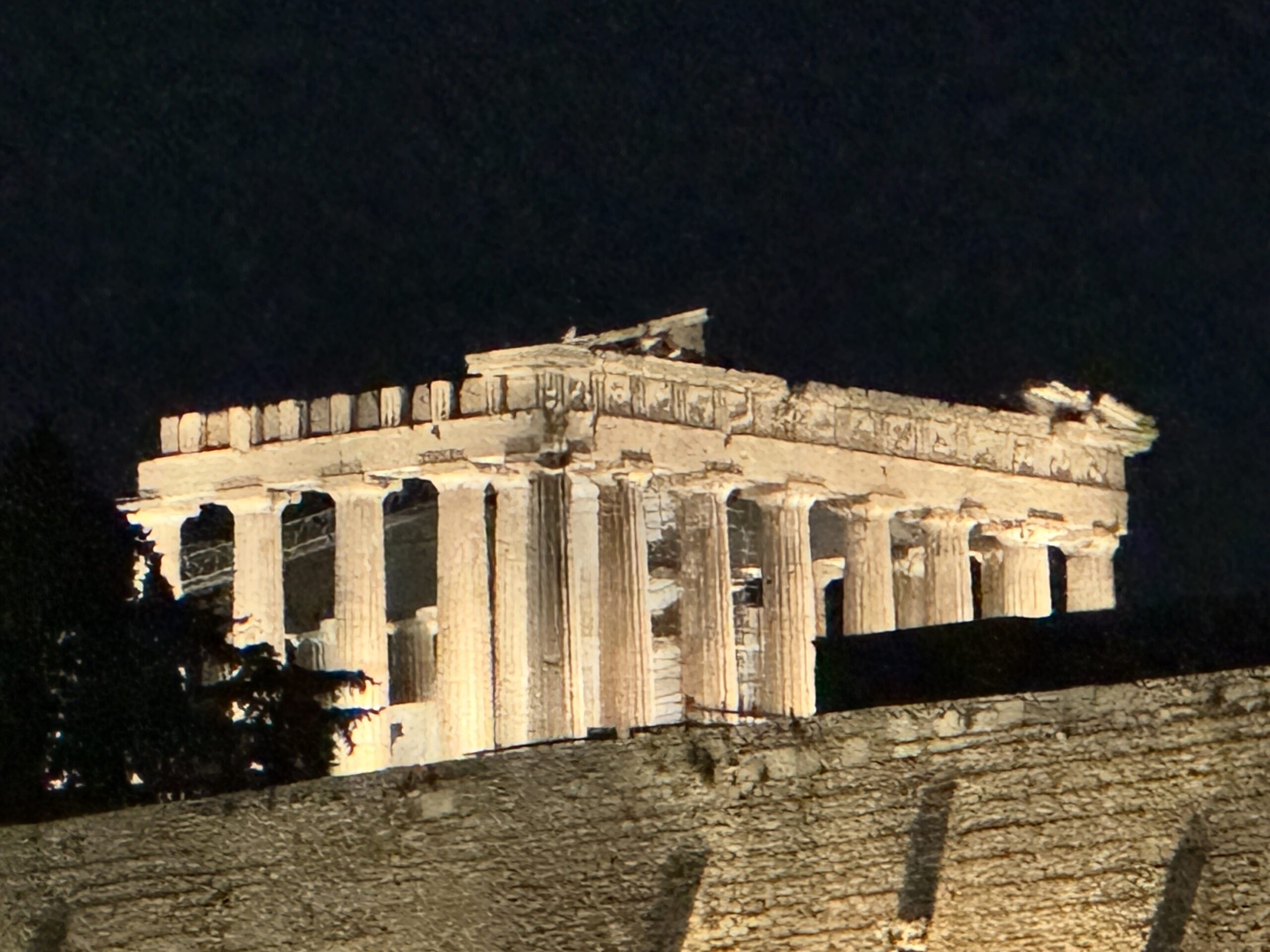 IMG_9990 Parthenon view from hotel - Taussig Travel Night view of a classical stone ruin with a row of tall columns, illuminated against a dark sky.